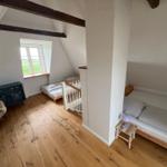Zimmer mit Holzboden, Fenster und zwei Betten unter Dachschrägen.