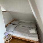 Schlafzimmer mit Doppelbett, Holzboden und Stehlampe.