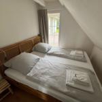 Schlafzimmer mit Doppelbett, Fenster und Holzgestell.