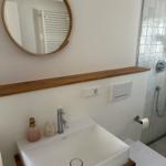 Badezimmer mit Waschbecken, Spiegel und Dusche.