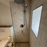 Duschkabine mit Duschbrause, Fenster und Toilette