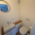 Badezimmer mit Waschbecken, Spiegel und Toilette.