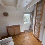 Raum mit Holzboden, Treppe und Fenster zur Außenseite.