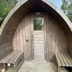 Holzschuppen mit Tür und zwei Bänken an den Seiten