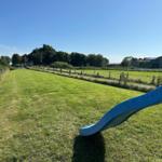 Blauer Rutsche im grünen Garten mit Blick auf Felder und Gebäude.