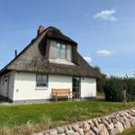 Haus mit Strohdach, Holzbank und Steinmauer im Garten.