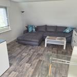 Living room with corner sofa, glass table, and wooden floor.