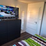 Bedroom with bed, wardrobe, and TV on dresser.