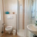 Badezimmer mit Dusche, Waschbecken und Toilette. Wand- und Bodenfliesen.