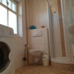 Badezimmer mit Dusche, Toilette, Waschmaschine und Waschtisch.
