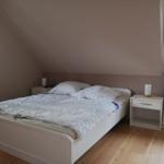 Schlafzimmer mit Dachschrägen, weißem Bett und zwei Nachttischen.