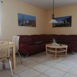 Wohn- und Essbereich mit rotem Sofa, Holztisch und Wandbildern.