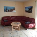 Roter Ledersofa im Wohnzimmer mit runden Tisch und Wandbildern.