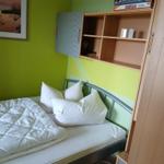 Ein Schlafzimmer mit Bett, Schrank und Regal an der Wand.