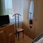 Schlafzimmer mit Kleiderschrank, Stuhl und TV-Schrank vor Fenster