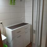 Badezimmer mit Dusche, Waschbecken und Schrank.