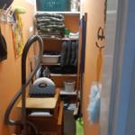 Kleiner Raum mit Schrank, Staubsauger und Reinigungsmitteln.