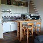 Küche mit Barhocker und Kochgeräten an der Wand