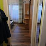 Schlafzimmer mit Holzboden, Gardinen und Schrank