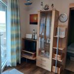 Wohnzimmer mit Fernseher, Glasvitrine und Balkonzugang.