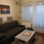 Wohnzimmer mit Sofa, Couchtisch und Fenster mit Vorhängen.