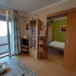 Wohnbereich mit Balkon, Schrank und Blick in Schlafzimmer.