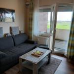 Wohnzimmer mit Sofa, Couchtisch und Balkon mit Blick auf Felder.