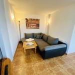 Wohnzimmer mit Ecksofa, Holztisch und Wandbild