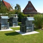 Drei Strandkörbe mit blau-weißen Streifen stehen auf einer Terrasse im Garten.