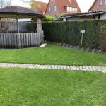 Garten mit Pavillon, Rasenfläche und Fahrradständern an der Hecke.