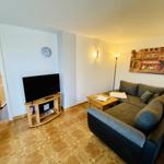 Wohnzimmer mit Sofa, Fernseher und Holzboden