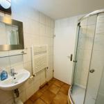 Badezimmer mit Dusche, Waschbecken und Spiegel an der Wand.