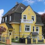 Gelbes Haus mit Balkon und Flagge vor blauem Himmel
