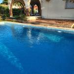 Pool mit Blick auf Terrasse und Bogenarkadenhaus