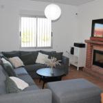 Wohnzimmer mit Sofa, Kamin und Fernseher an der Wand.