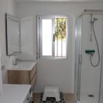 Badezimmer mit Dusche, Waschbecken und Fenster.