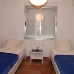 Zwei Einzelbetten mit blauen Decken und einem Nachttisch mit Lampe.