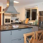 Moderne Küche mit Edelstahlgeräten und Holzstühlen an der Insel.