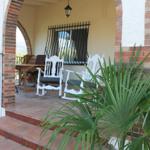 Terrasse mit weißen Schaukelstühlen, Tisch und Blick auf Berge.