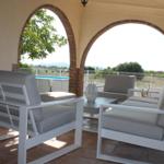 Terrasse mit weißen Sitzmöbeln und Blick auf Pool und Landschaft.