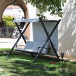 Schwinger mit Sonnenschutz im Garten neben Pool und Sitzgelegenheiten.
