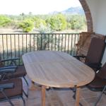 Terrasse mit Holztisch und Stühlen, Blick auf grüne Landschaft und Berge.