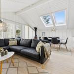 Living room with sofa bed, dining area, and skylights. Wooden floor and white walls.