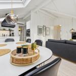 Dining area with white table and gray sofa. Kitchen and living room are connected.