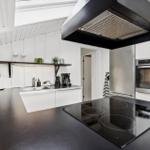 Modern kitchen with black countertop, stainless steel appliances, and white cabinets.