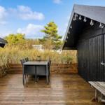 Terrace with table, chairs, and wooden deck. Background: grass and trees under blue sky.