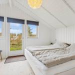 Bedroom with double bed, windows, and door to green outdoor area.