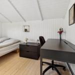 Bedroom with bed, desk, and wall pictures.