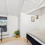 Bedroom with bed, table, plant, and window view.