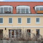A yellow building with a red roof and three rooftop terraces with balconies.